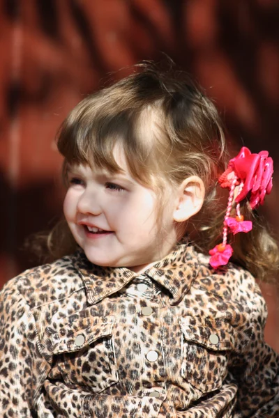 Pretty happy little girl with pink bows in overcoat looks away a — Stock Photo, Image