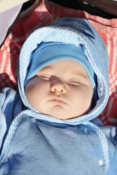 Lilla söta baby i blå tröja sover i buggy på solig dag. — Stockfoto