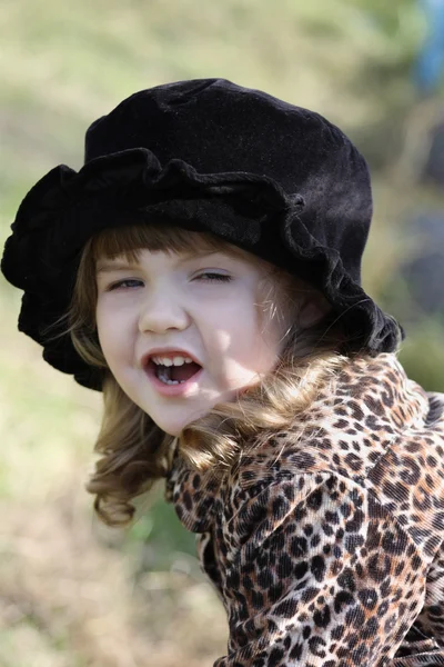 Beautiful little girl in black hat shouts outdoor at autumn day. — Stock Photo, Image