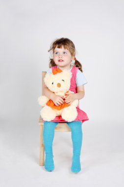 küçük şirin kız ahşap sandalye oyuncak ayı ile oturur ve aw görünüyor