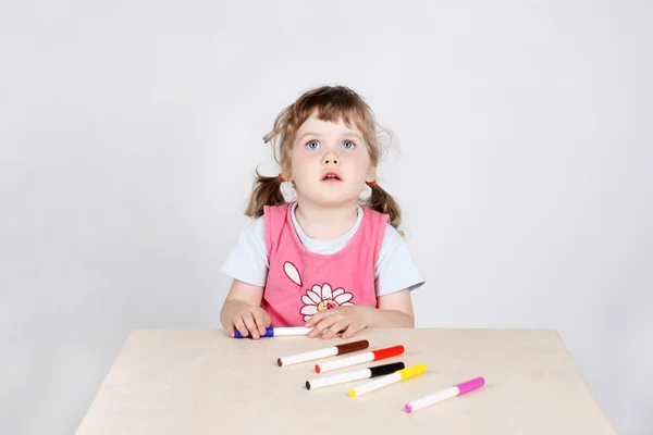 Little cute girl sits at wooden table with felt-tip pens and loo — Stock Photo, Image