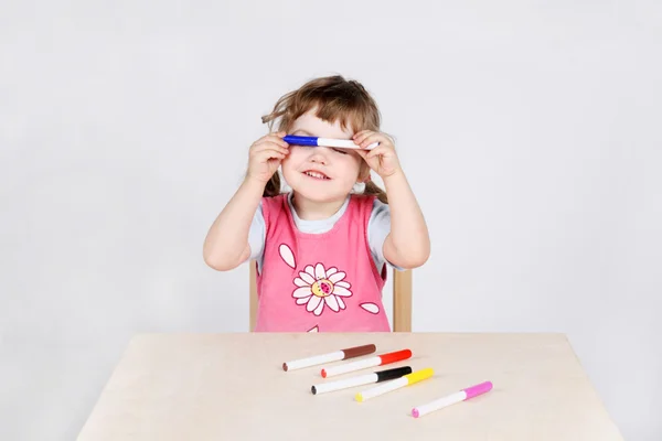 Niña linda se sienta en la mesa de madera y juega con la punta de fieltro pe — Foto de Stock