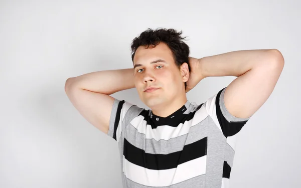 Brunet man in striped T-shirt smiles and stretches oneself on gr — Stock Photo, Image