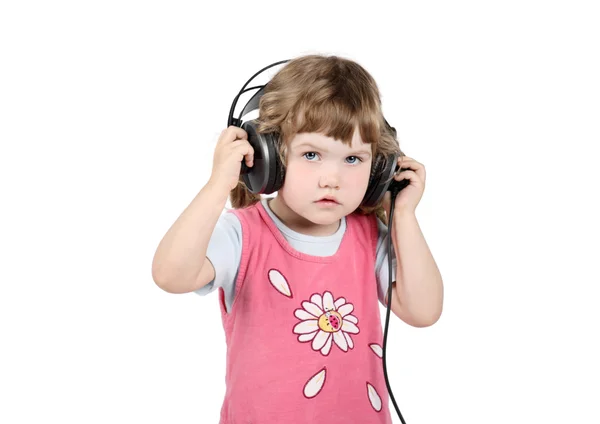 Little girl listens to music in big headphones and looks at came — Stock Photo, Image