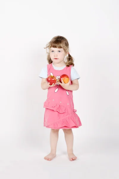 Petite fille pieds nus heureux tient deux pommes rouges dans les mains sur whit — Photo