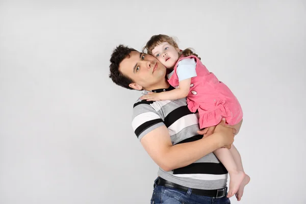 Felice padre tiene e abbraccia il suo piccolo carino figlia su grigio bac — Foto Stock