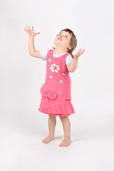 Little barefoot girl in pink with raised hands looks up on white — Stock Photo, Image