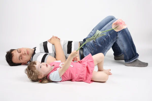 Happy father and talking little daughter with flower lie on floo — Stock Photo, Image