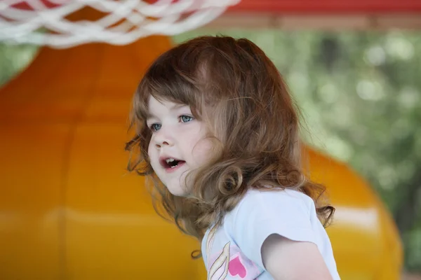 Pequena menina muito feliz no trampolim inflável amarelo parece um — Fotografia de Stock