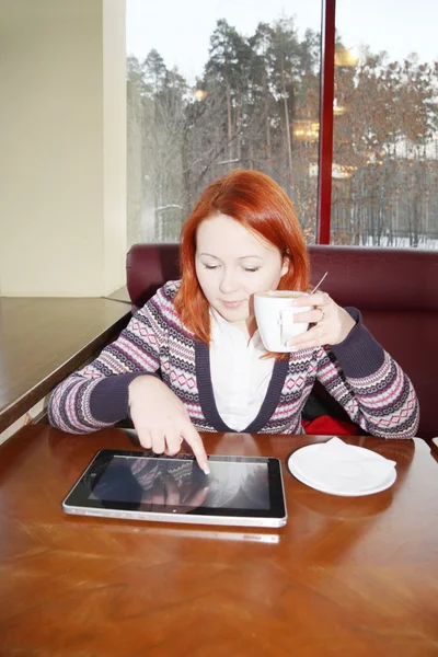 Redhead girl with cup of coffee sit at table in cafe with tablet pc. — Stock Photo, Image