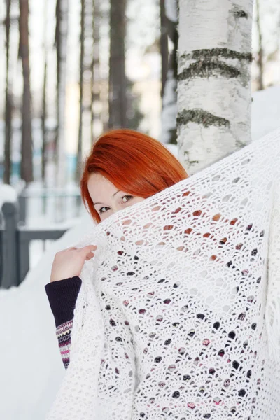 Cute girl hides her face behind shawl near birch at winter fores — Stock Photo, Image