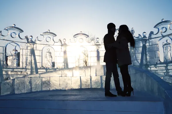 Silueta de pareja joven cerca de la pared de hielo con esculturas en el invierno —  Fotos de Stock