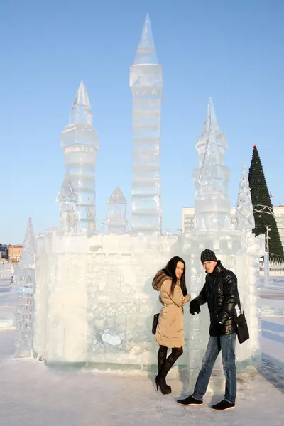 Young beautiful couple stand neat ice castle at sunny winter day — Stock Photo, Image