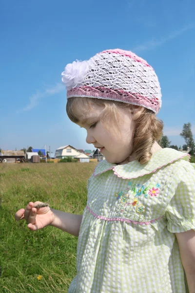 Bambina guarda lama di villaggio erba in estate giornata di sole — Foto Stock