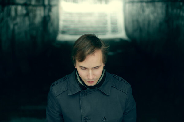 Young man in black comes out small tunnel at winter night and lo