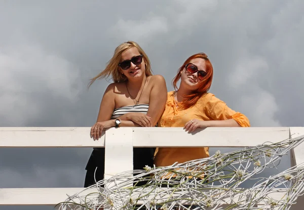 Two happy girls in sunglasses stand on white bridge at summer da — Stock Photo, Image