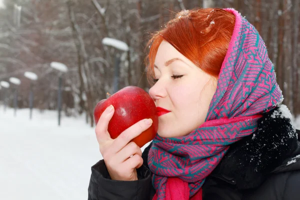 Pretty girl in red kerchief holds big red apple outdoor at winte — Stock Photo, Image