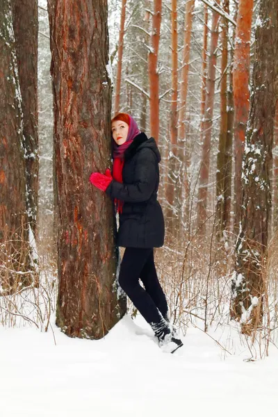 Beautiful girl stands next to large tree and looks up outdoor at — Stock Photo, Image