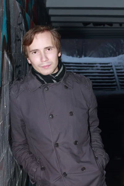 Young man stands and holds hands in pockets in small tunnel at — Stock Photo, Image