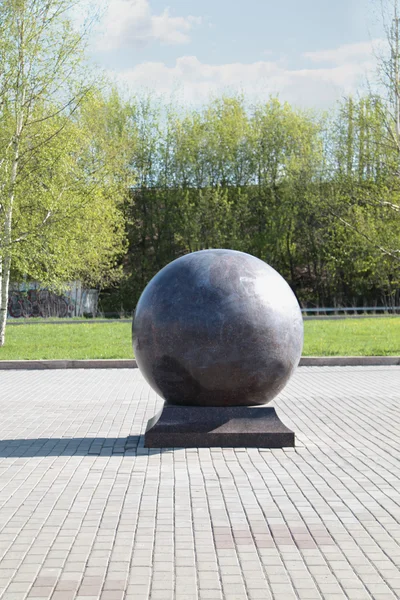 Palla di granito di grandi dimensioni su stand della pavimentazione nel parco al sole estivo — Stockfoto