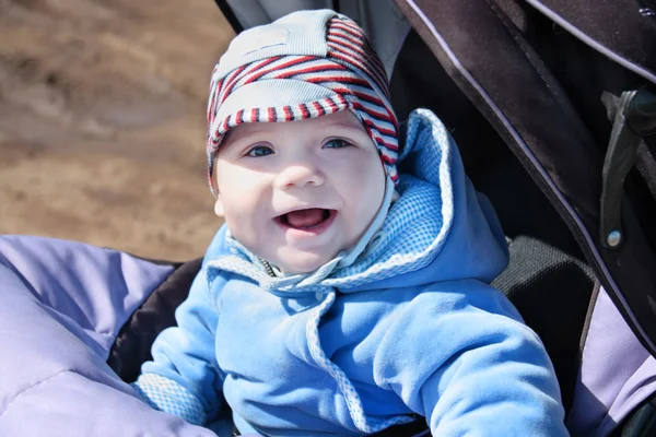 Liten glad bebis i blå overaller i vagnen utomhus på soliga d — Stockfoto