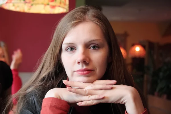 Молодая женщина сидит за столом ресторана, улыбается и смотрит в камеру — стоковое фото
