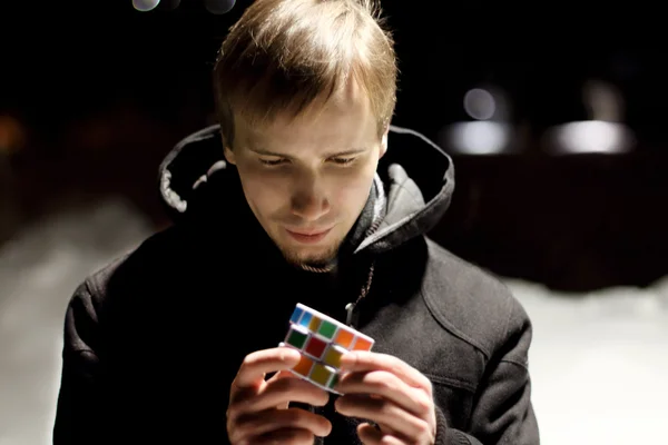 Junger schöner Mann steht draußen mit Rubik-Würfel in der Winternacht — Stockfoto