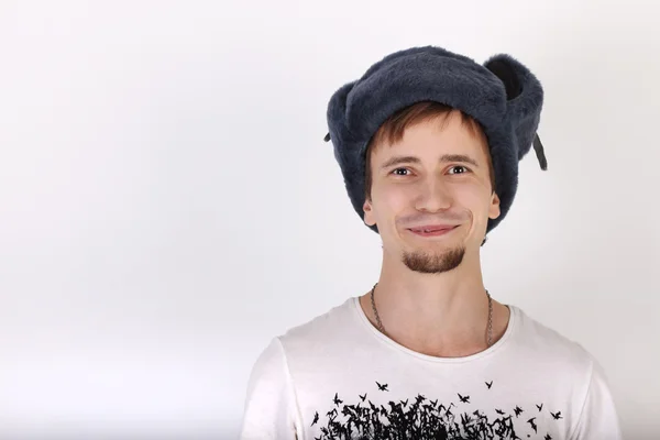 Feliz joven guapo en gorra gris con orejeras sonríe en stu —  Fotos de Stock