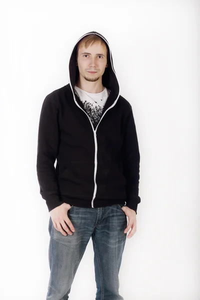 Young handsome man in black hoodies and jeans looks at camera in — Stock Photo, Image