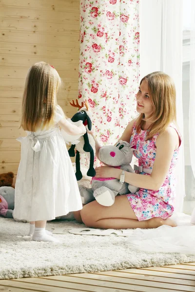 Linda menina loira e sua mãe brincam com brinquedos macios nea — Fotografia de Stock