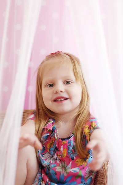 Pretty little girl sits among transparent curtains and stretches — Stock Photo, Image