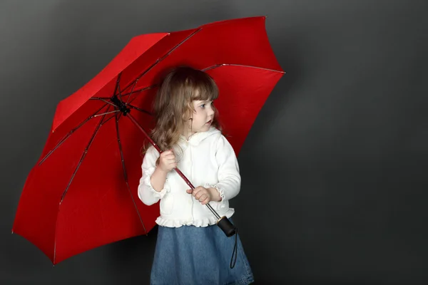 Little girl with flowing hair standing under large red umbrella — Stock Photo, Image