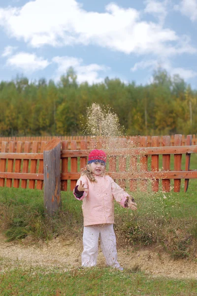 Fun girl throws up dust near wooden fence — Stock Photo, Image