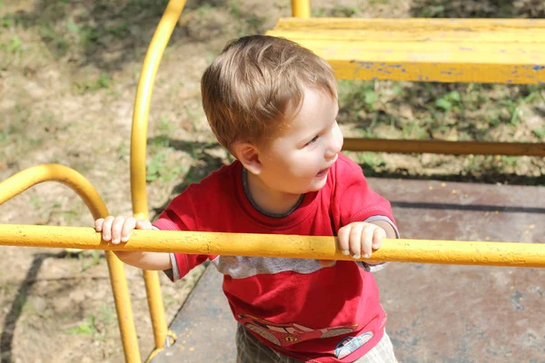 Happy little child plays on yellow swing rocking — Stock Photo, Image