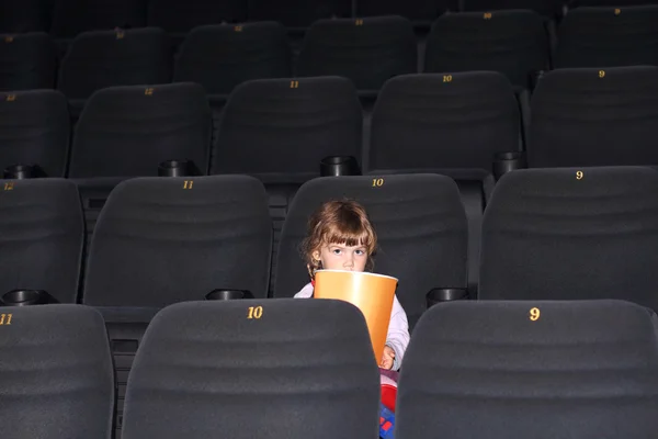 Dziewczynka z dwoma oplotami z dużą część popcorn siedzi w sali kina — Zdjęcie stockowe