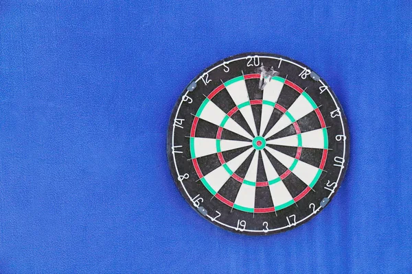 Γύρο dartboard με αριθμούς και με ακόντια σε μπλε τοίχο — Φωτογραφία Αρχείου