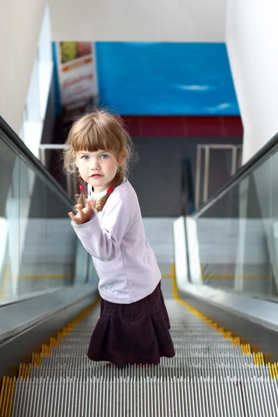 Little girl with two pigtails coming down escalator Stock Photo