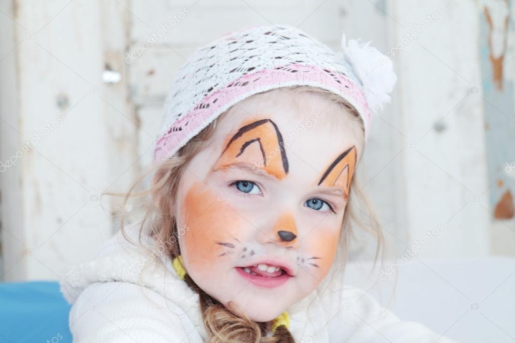 Little beautiful girl with face painting of orange fox poses in 
