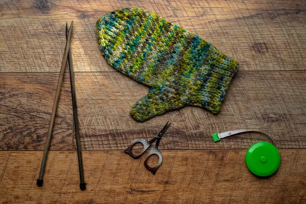 Grüne Strickhandschuhe auf einem hölzernen Hintergrund — Stockfoto