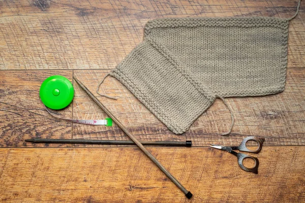 Strickmuster aus beigem Garn, Holzhintergrund im Test einer Wolle mit Strickstück. — Stockfoto