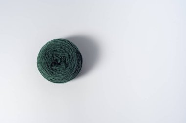 Beyaz arkaplanda büyük koyu yeşil iplik yumağı