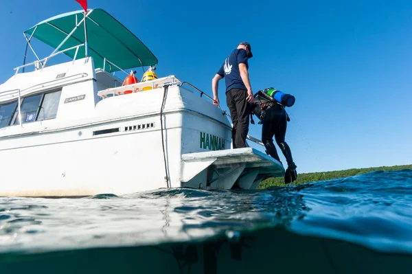 Munising, MI -August 14th, 2021: Boat Captain helping SCUBA diver out of water — Stock Photo, Image