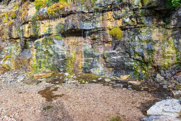 Eau souterraine naturelle pleurant à travers un mur de grès — Photo