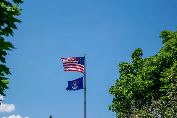Flag of Michigan and the United State flying on poles — ストック写真