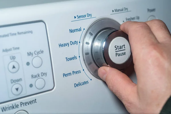 Hand turning the knob of the dryer to adjust the setting. — Foto de Stock