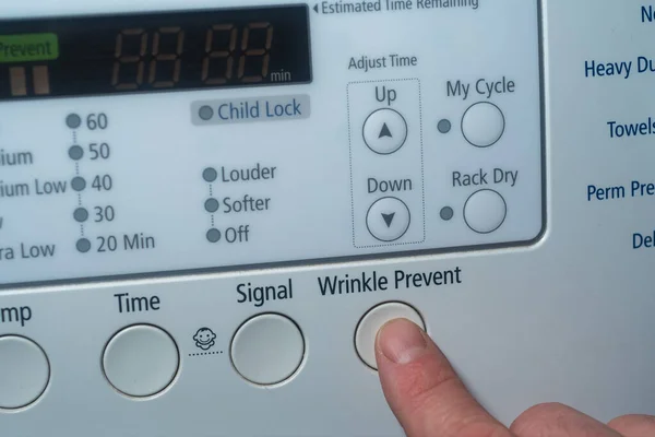 Finger pushing wrinkle prevent button on electric dryer — Foto de Stock