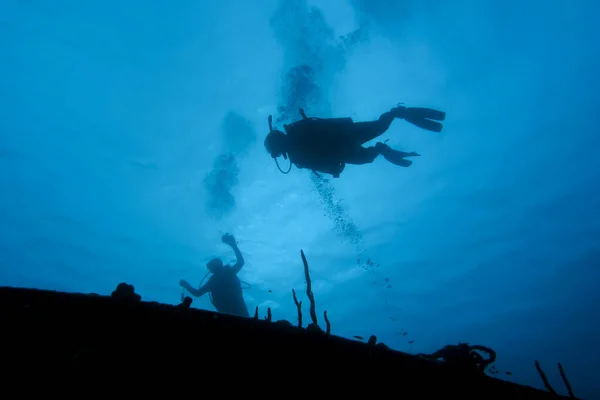 Plongeur sous-marin planant au-dessus d'une épave en silhouette — Photo