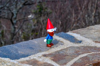 Gnome hiking in the mountains on a rock ledge