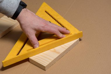 Marangoz tahta üzerinde çapraz çizgi çizmek için eski bir kare kullanıyor.