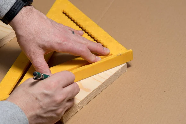 Ξυλουργός χρησιμοποιώντας ένα μολύβι και παλιό τετράγωνο σήμανση διαγώνια γραμμή σε μια ξύλινη σανίδα — Φωτογραφία Αρχείου